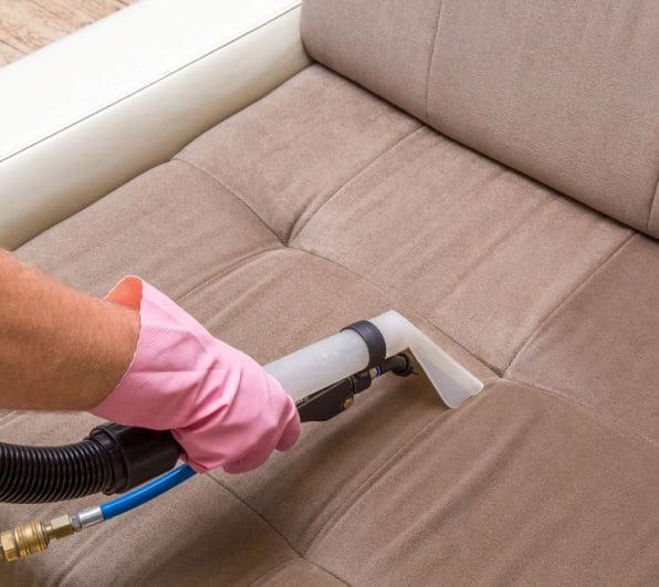 A person in pink gloves cleaning the couch.