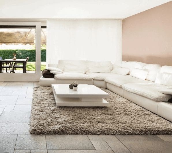 A living room with white furniture and a rug.