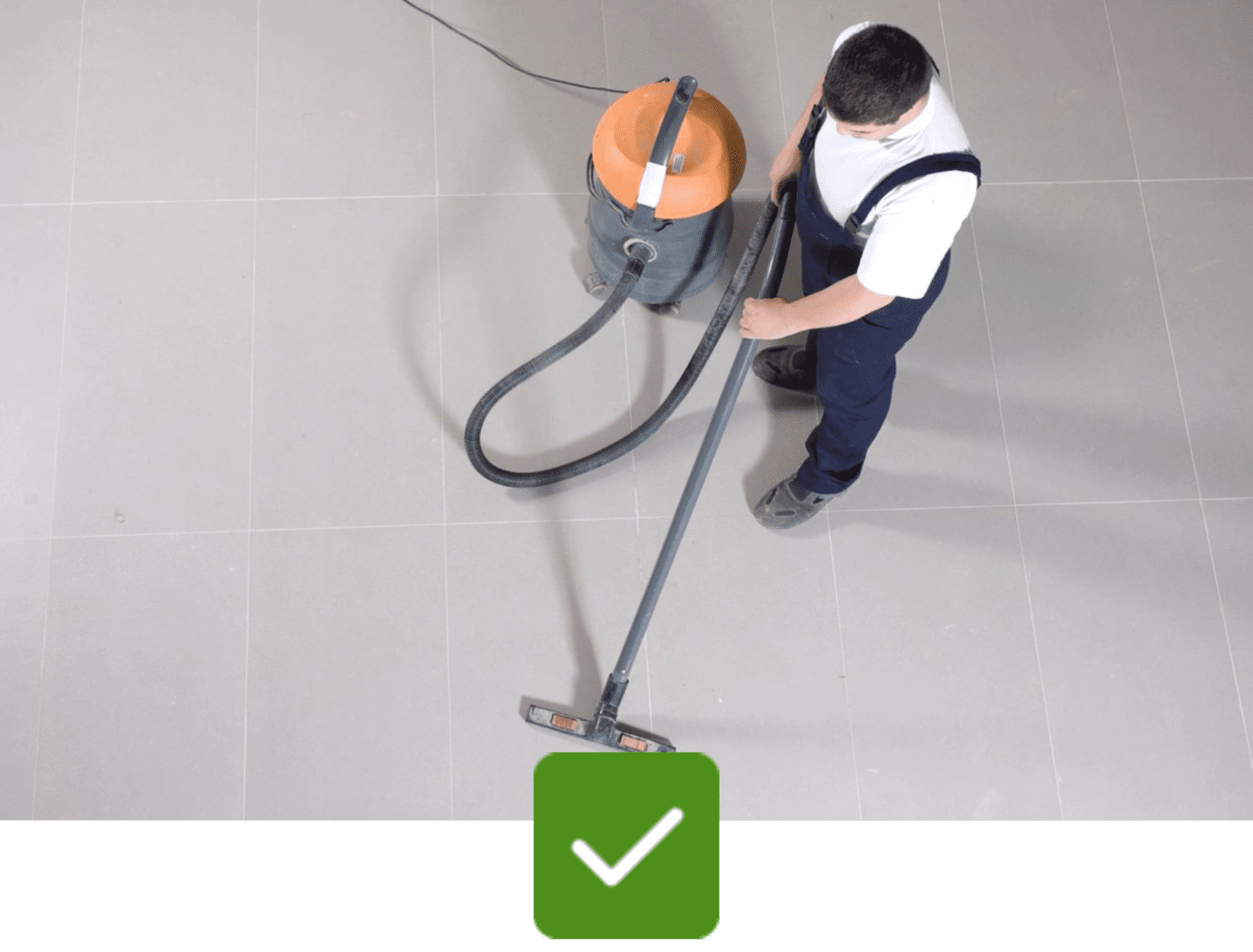 A man is vacuuming the floor with an orange vacuum.